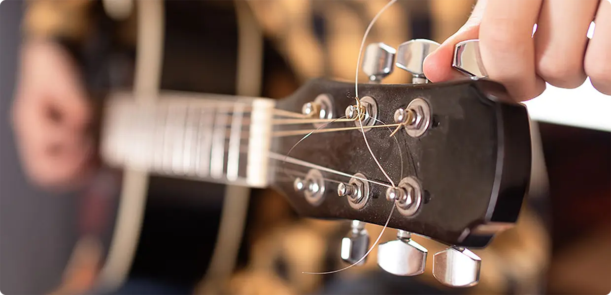   A child tuning a guitar using a clip-on tuner.  
